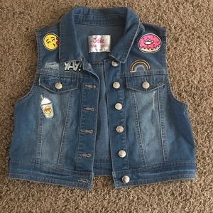 Distressed light wash denim vest with patches.